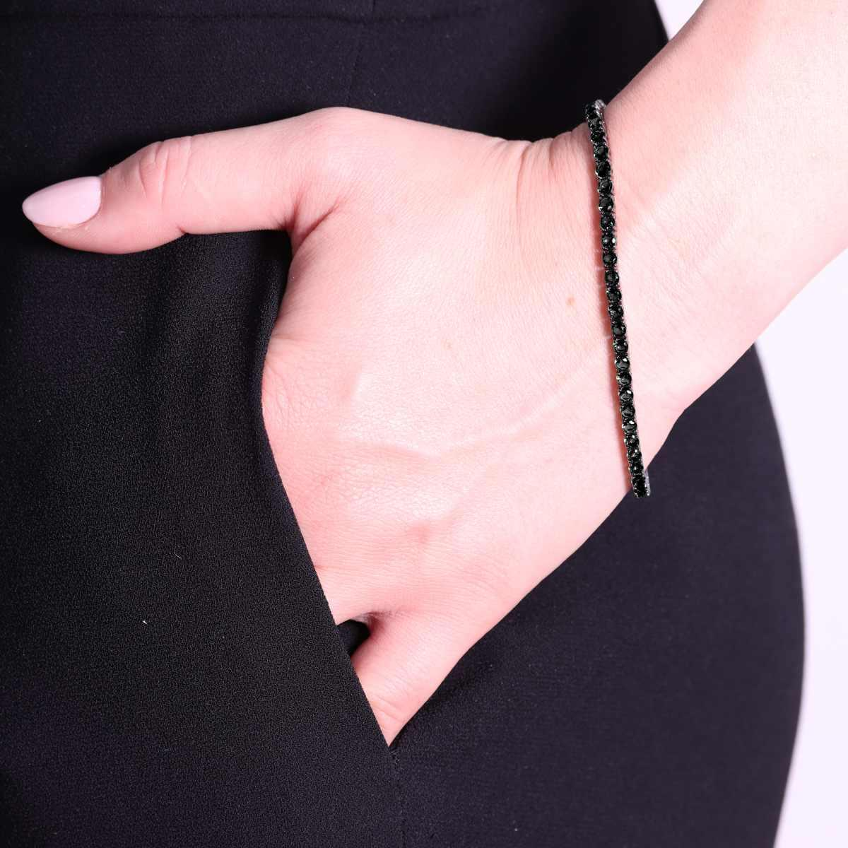 Donna con un braccialetto di zirconi neri al polso, con la mano in tasca.