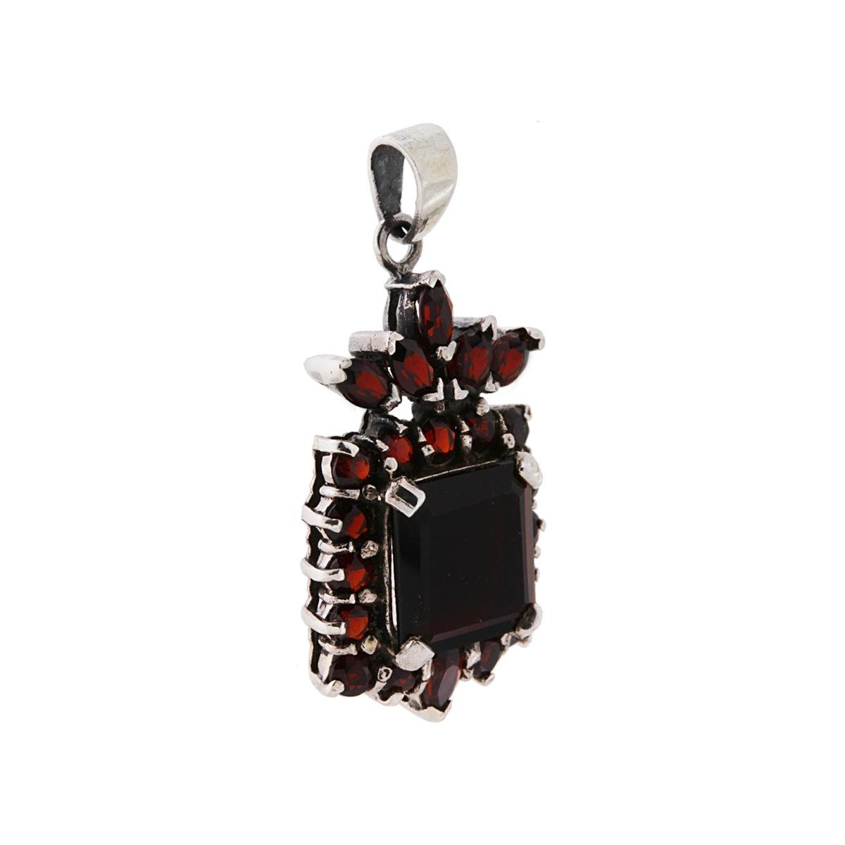 Ciondolo in argento con una grande pietra centrale color rubino e piccole pietre a forma di foglia.