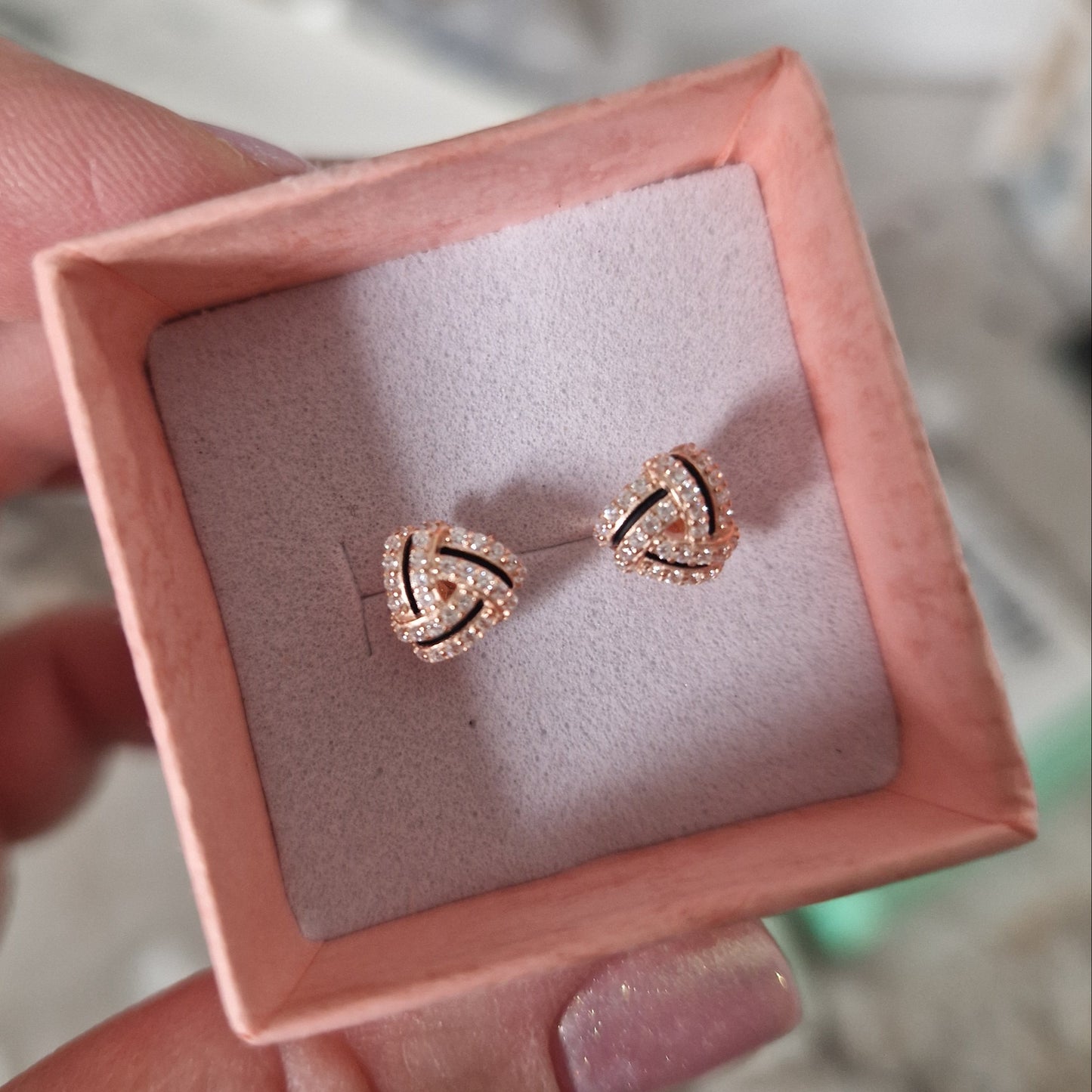 Orecchini a perno a forma di triangolo intrecciato, placcati in oro rosa, con pavé di zirconi.