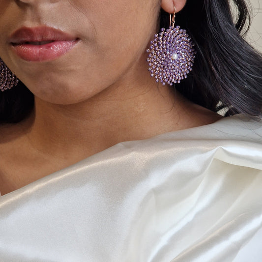 Donna con orecchini a cerchio viola realizzati con perline e perla centrale, che indossa un sari di raso bianco.