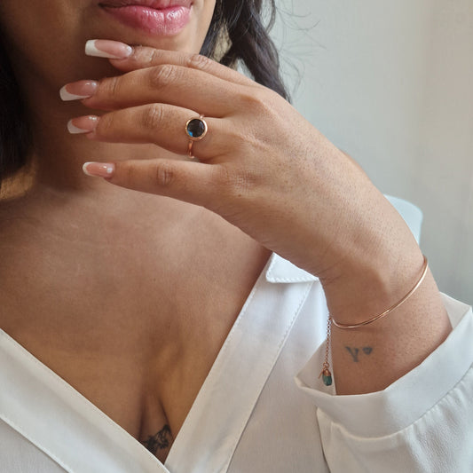 Donna indossa anello con pietra scura e un bracciale sottile. Le sue unghie sono lunghe con french manicure.