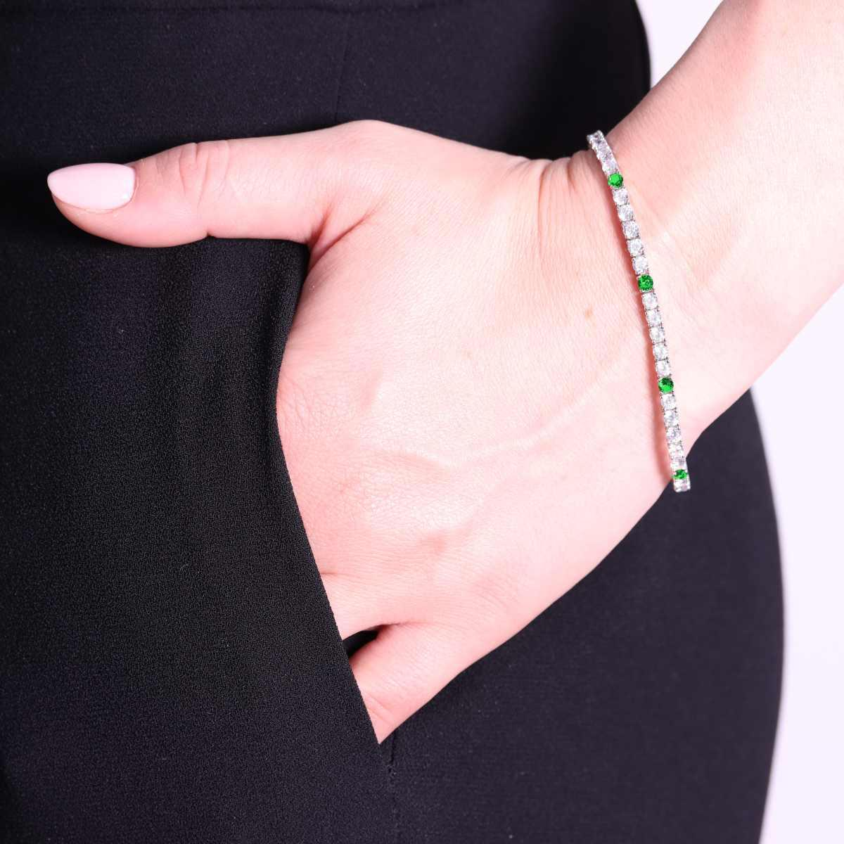Braccialetto a tennis con pietre preziose bianche e verdi, indossato da una donna.