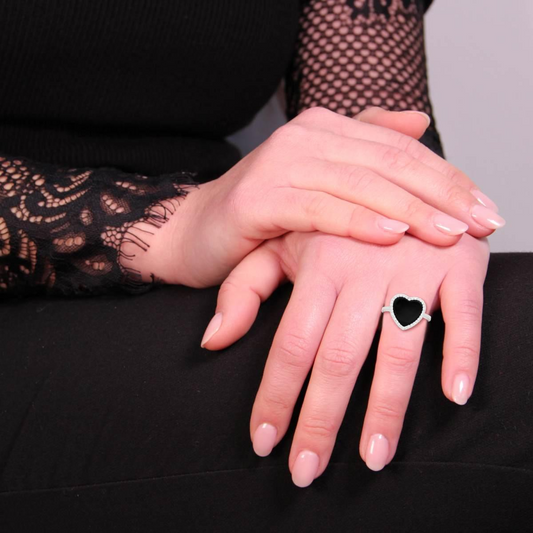 Anello con cuore in onice nero e diamanti indossato su una mano.