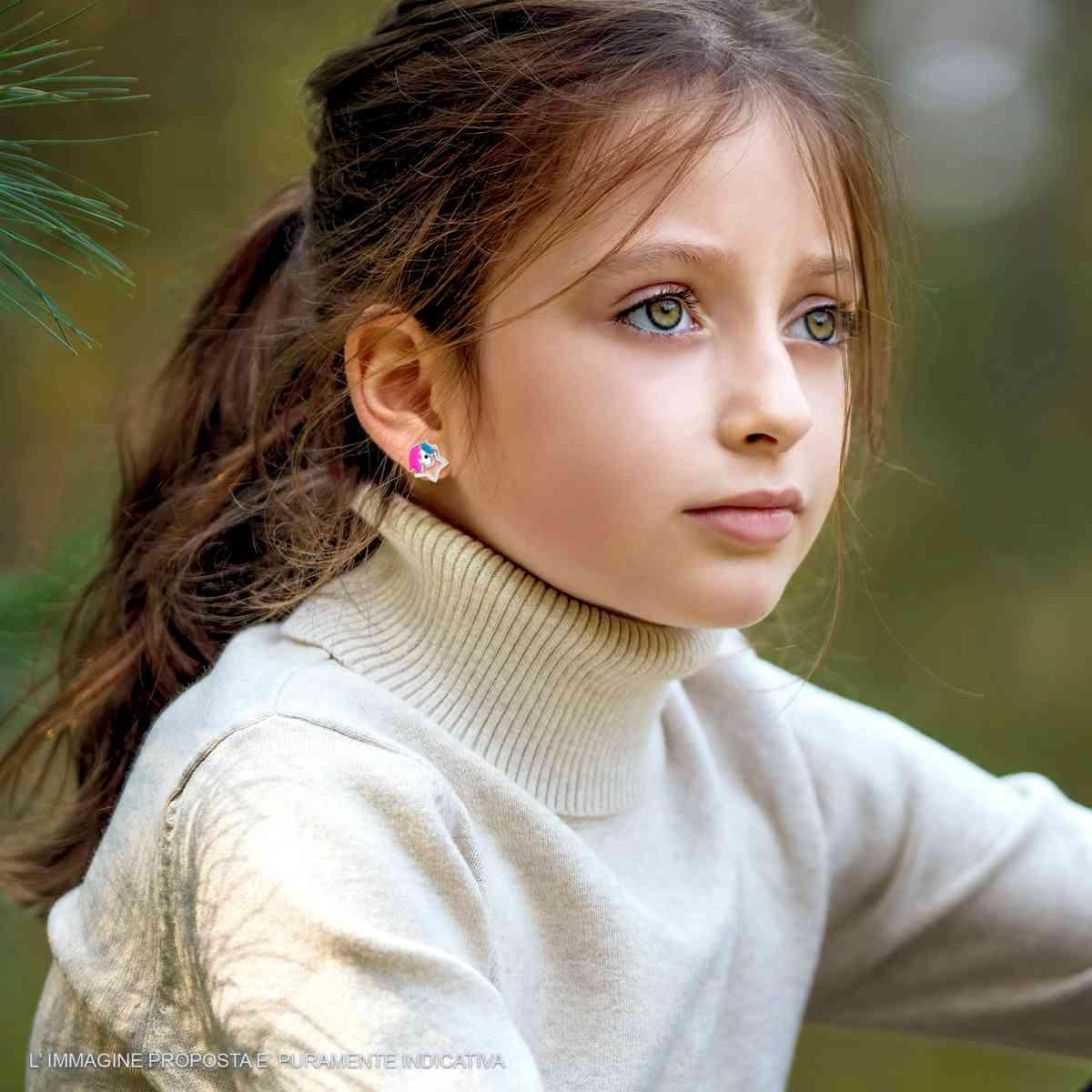 Bambina con un maglione a collo alto e orecchini a forma di fiorellino colorato.