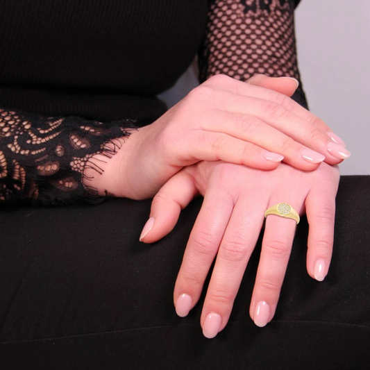 Anello in oro con diamanti su una donna che si tocca le mani.