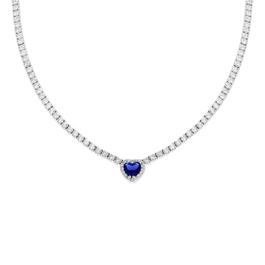Una delicata collana tennis in argento con uno zaffiro blu centrale a forma di cuore circondato da pietre di zirconia cubica bianca.