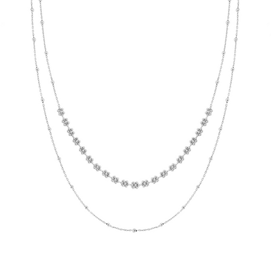 Collana a doppio filo in argento con piccoli ciondoli a fiore e perline, sfondo bianco.
