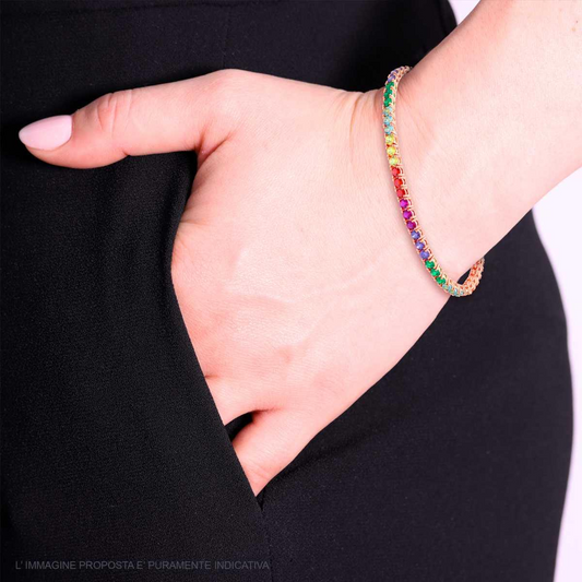 Bracciale tennis in oro rosa con zirconi colorati, indossato al polso di una donna con pantaloni neri.