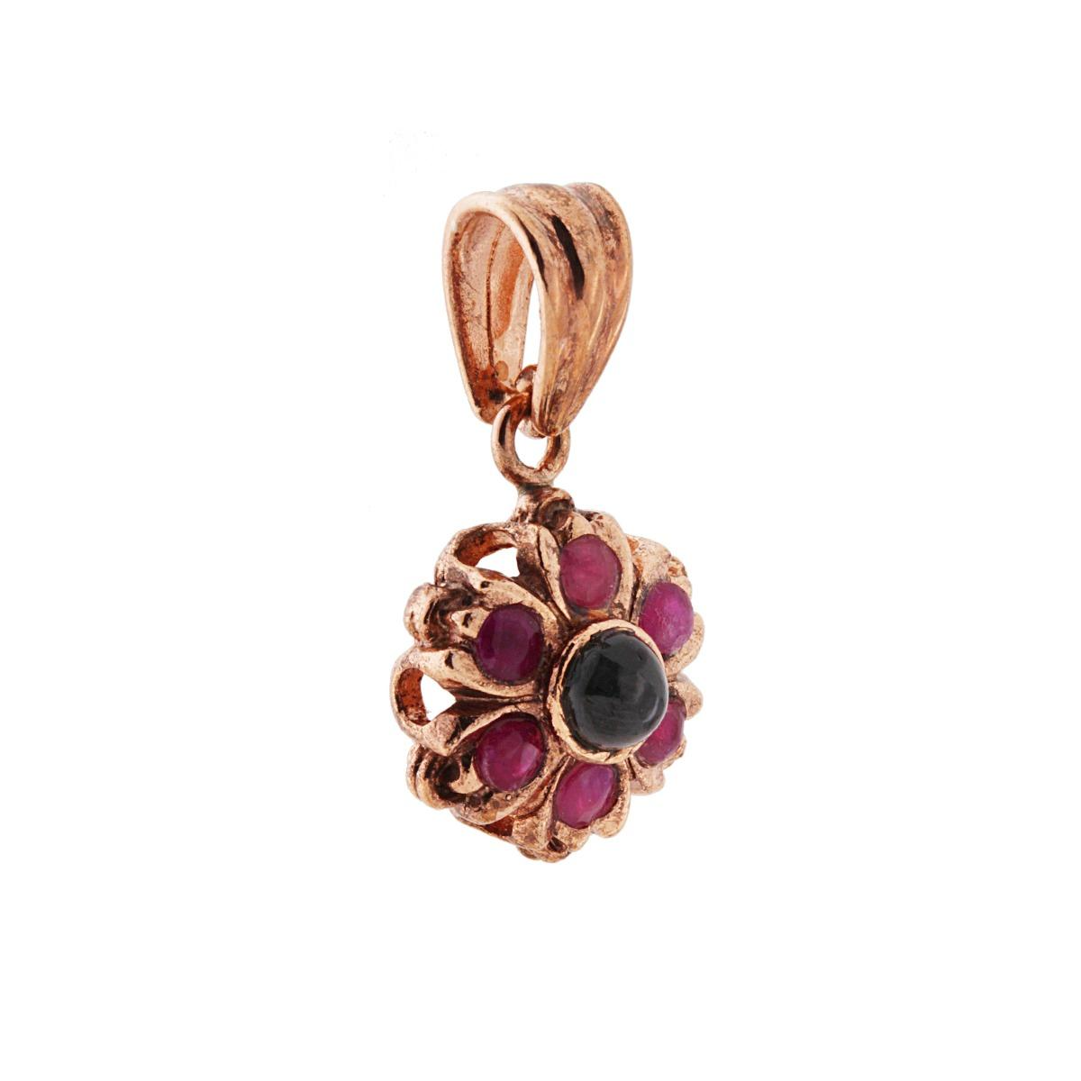 Ciondolo a forma di fiore in oro rosa con rubini e una pietra centrale nera.