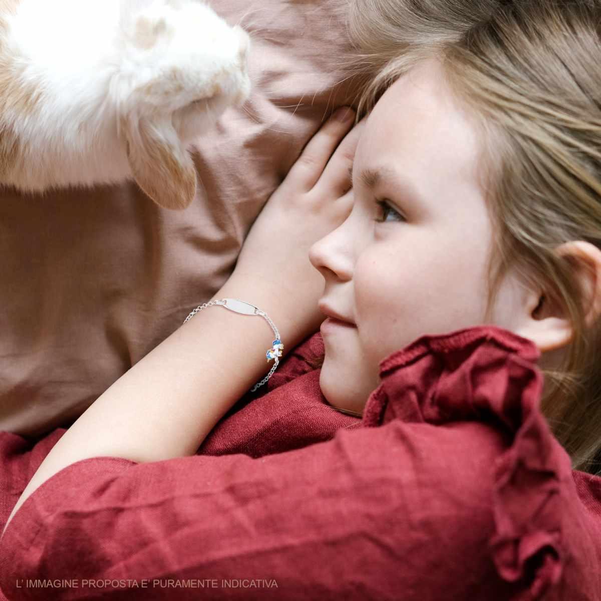Bambina con un braccialetto, distesa e guardando un coniglietto sopra di lei.