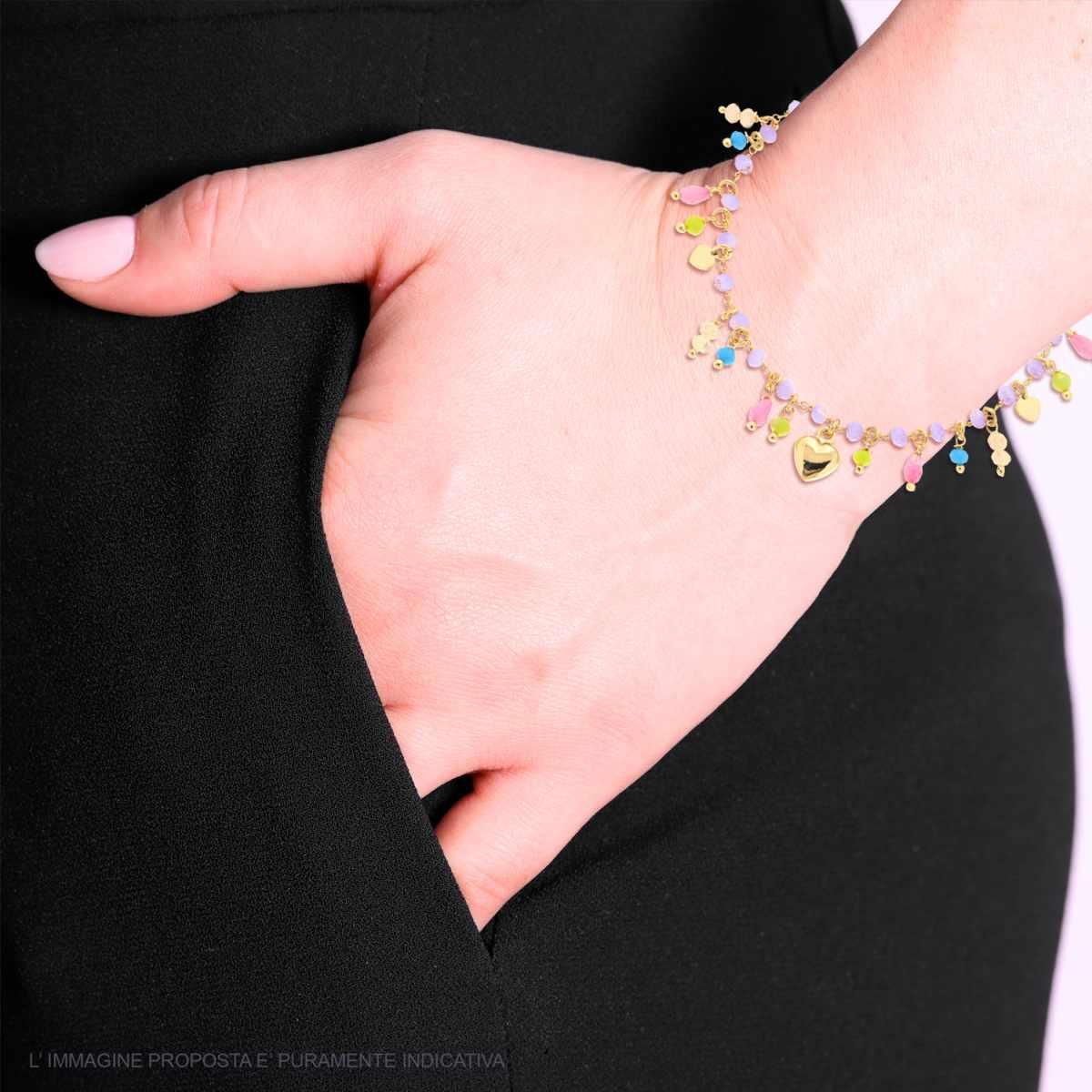 Donna con bracciale a catena dorata con charms a cuore e palline smaltate colorate, in mano in tasca.