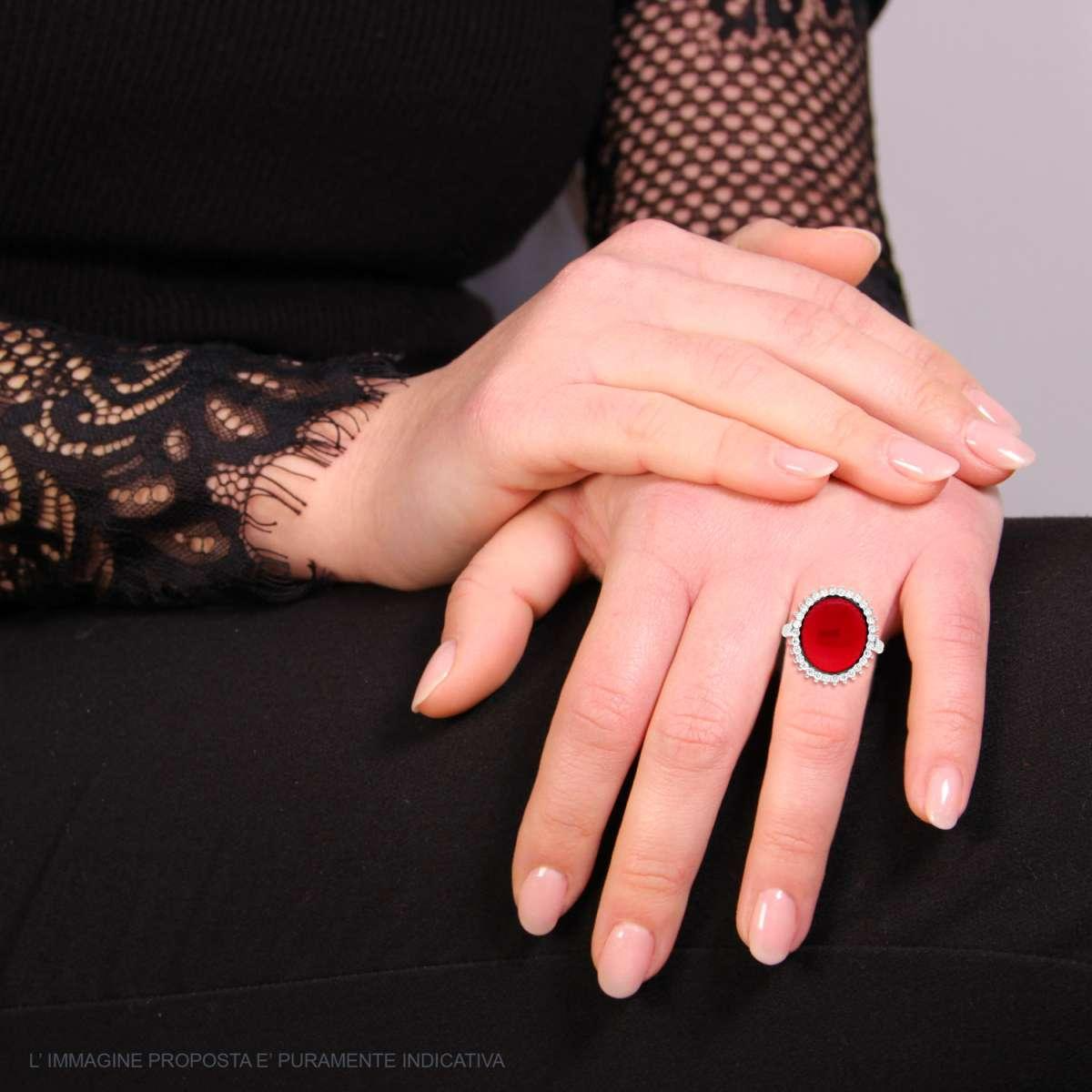 Anello con pietra rossa ovale e cornice di diamanti.