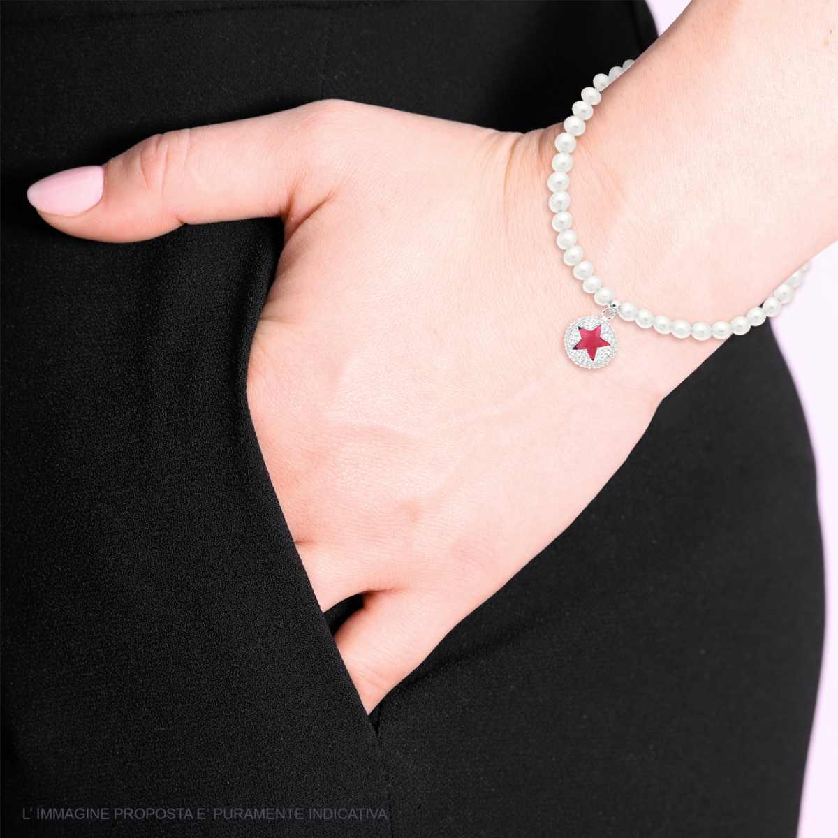 Una mano femminile con una giacca nera mostra un braccialetto di perle con un ciondolo a forma di stella rossa.