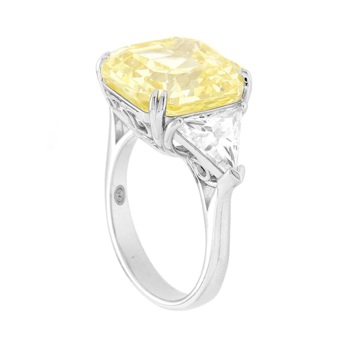 Anello in platino con diamante giallo a taglio cuscino e due diamanti bianchi a taglio triangolare.