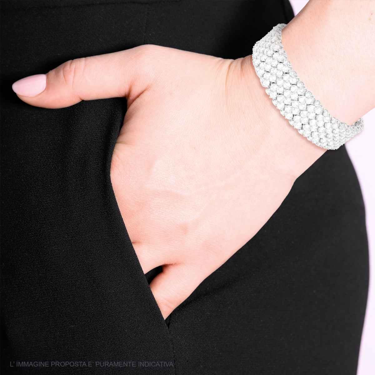 Una donna indossa un bracciale a maglia di perle bianche, con la mano in tasca.