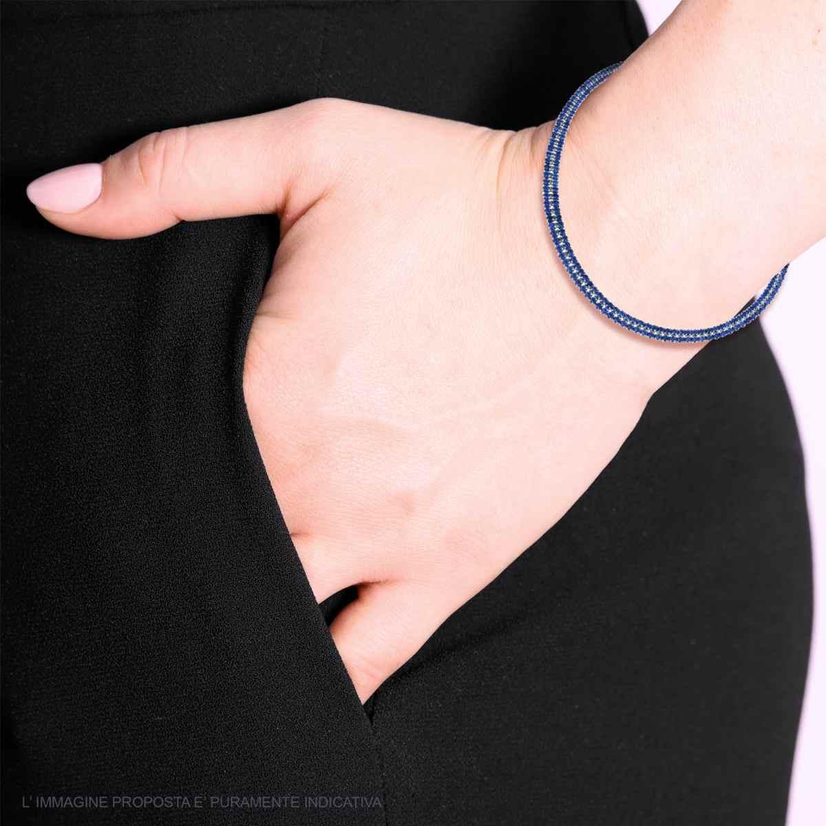 Braccialetto a filo blu su un polso di donna che tiene la mano in tasca.