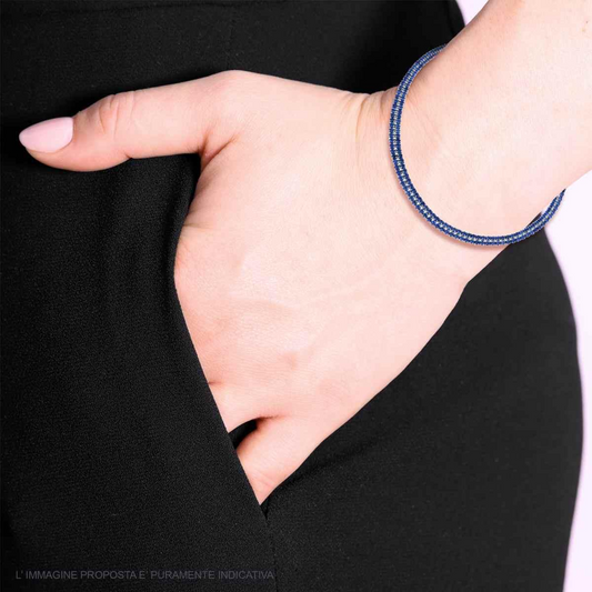 Braccialetto a filo blu su un polso di donna che tiene la mano in tasca.