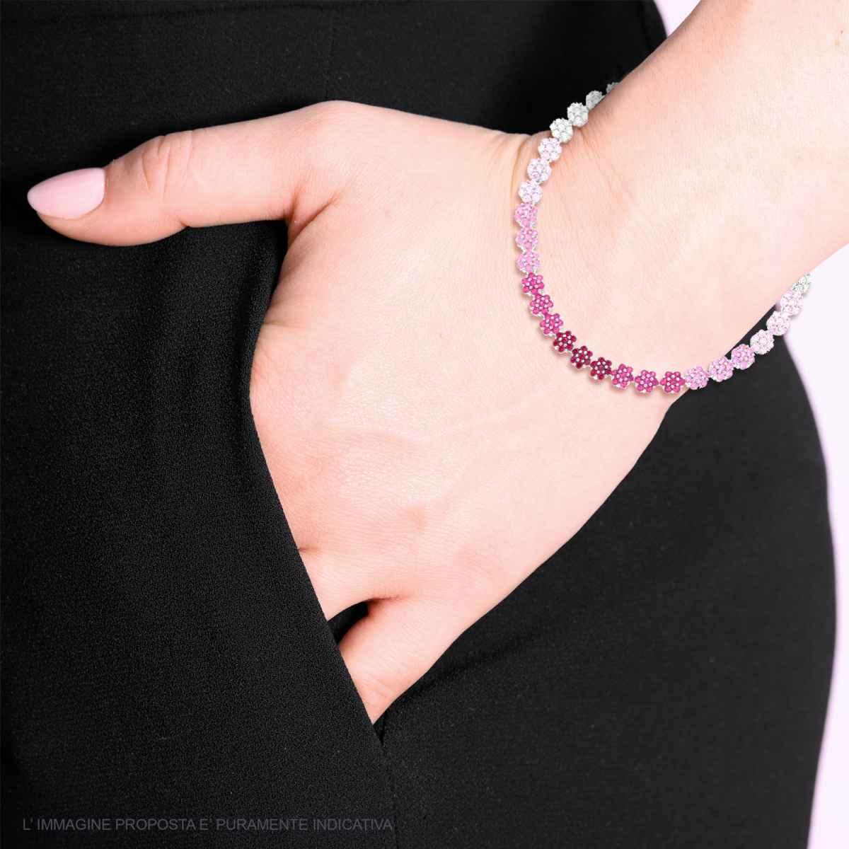 Bracciale a catena con sfumature di colore, da bianco a rosa scuro, indossato su un polso femminile.