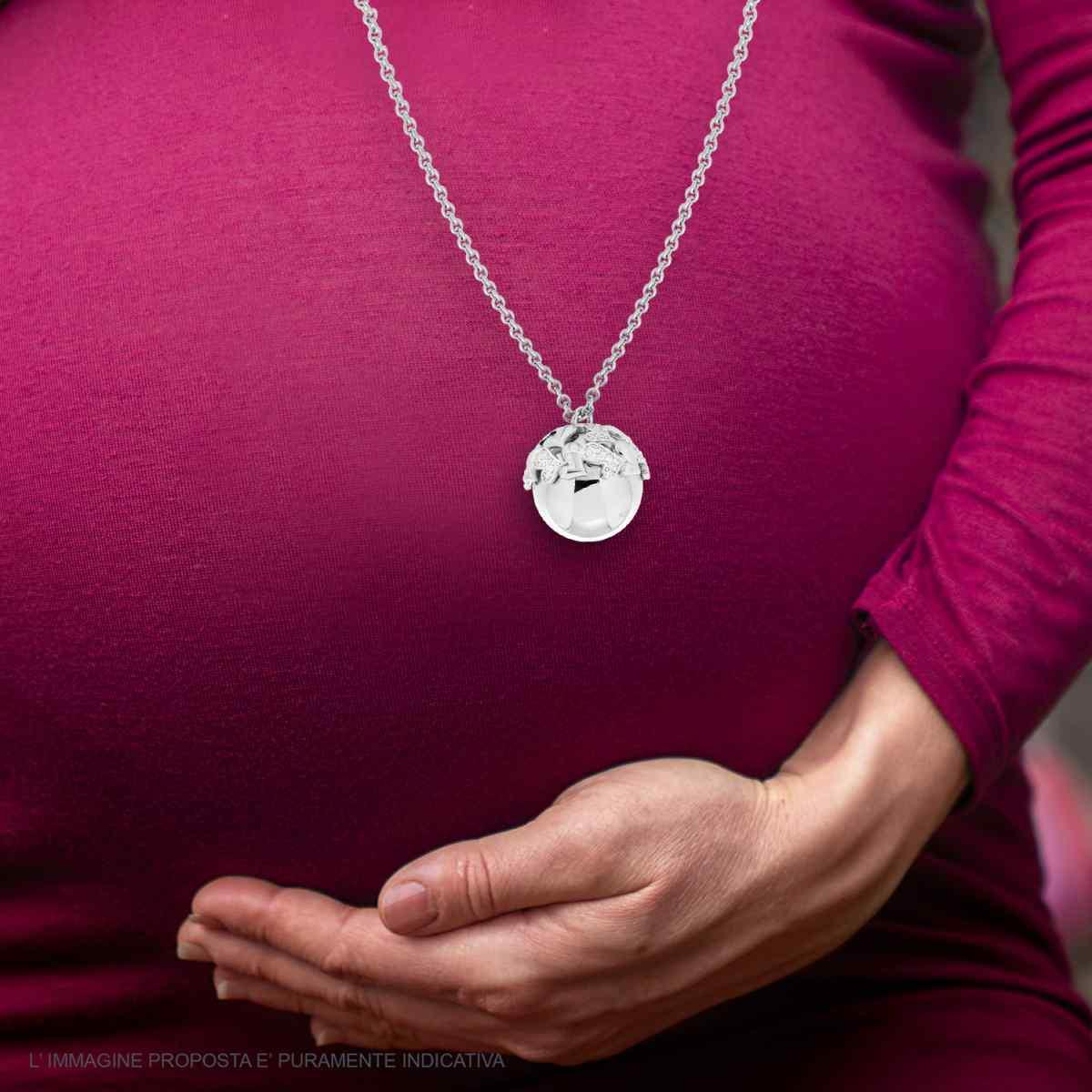 Pendente sferico su catena indossato da una donna incinta, con una mano appoggiata sul pancione.
