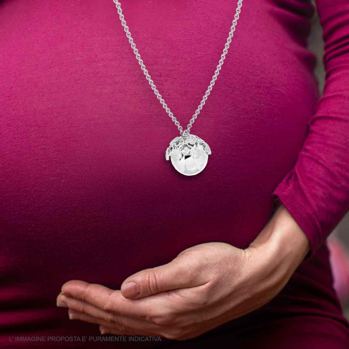 Donna incinta con ciondolo a sfera argentato sul pancione.