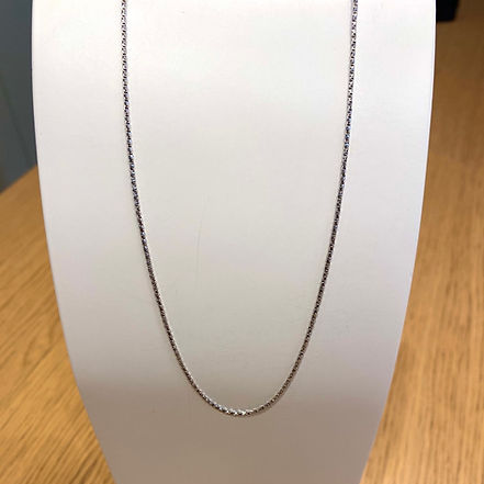 Collana a catena d'argento su un espositore bianco.