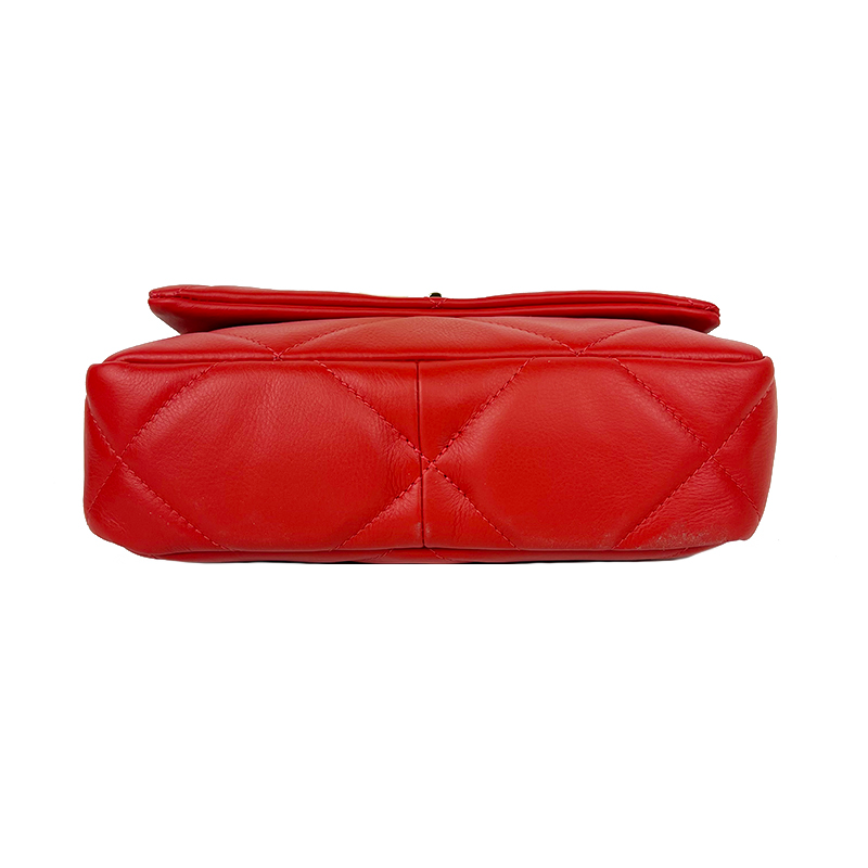 Parte inferiore di una borsa in pelle rossa matelassé, che mostra la cucitura a rombi e la struttura quadrata.