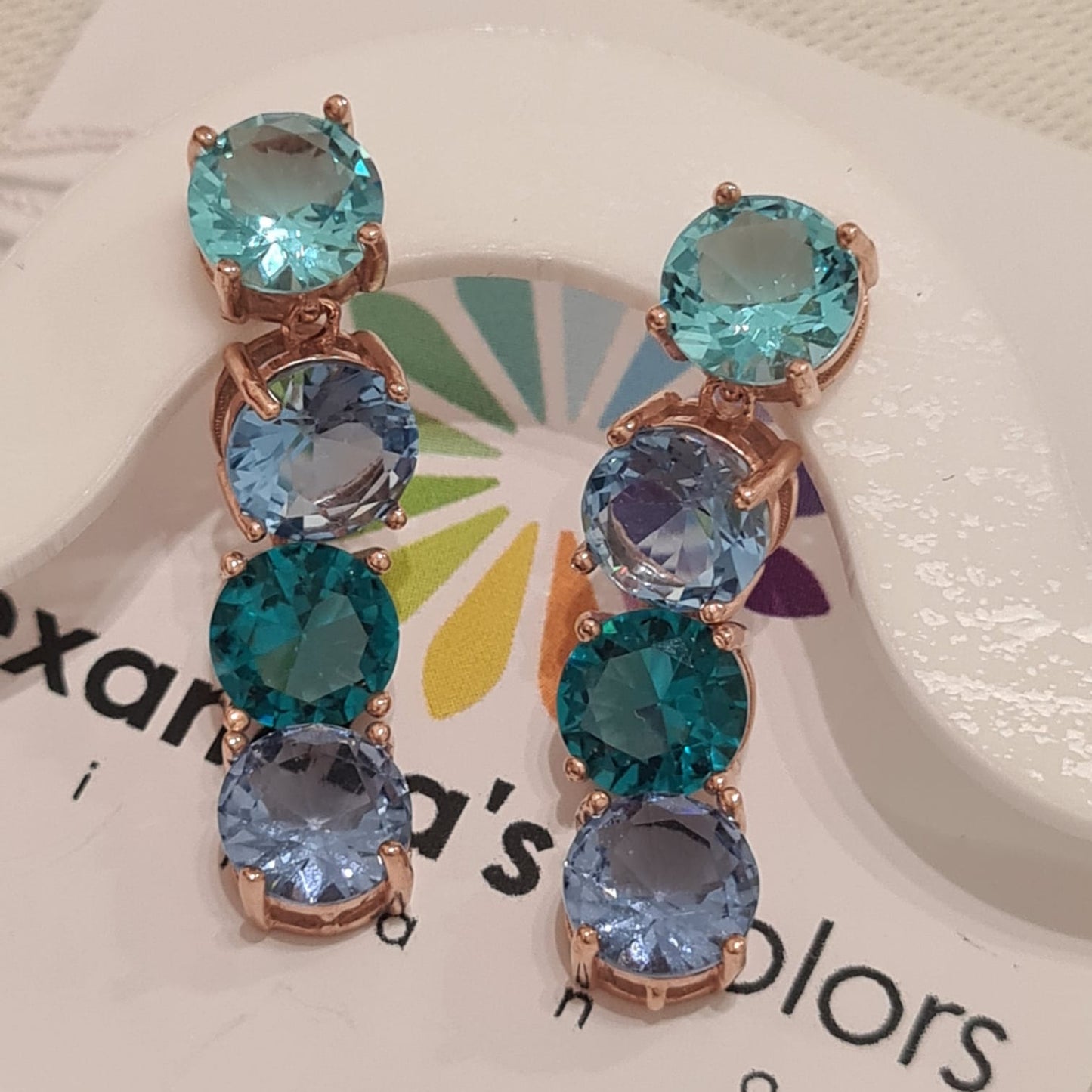 Orecchini pendenti con quattro pietre blu e verdi, incastonate in una montatura color oro rosa.