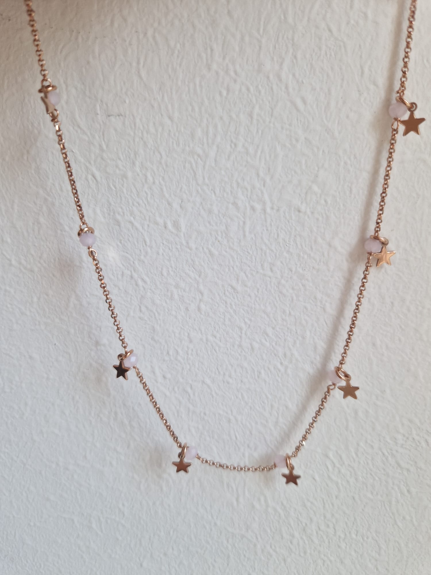 Una collana in oro rosa con piccole stelle e perle rosa.