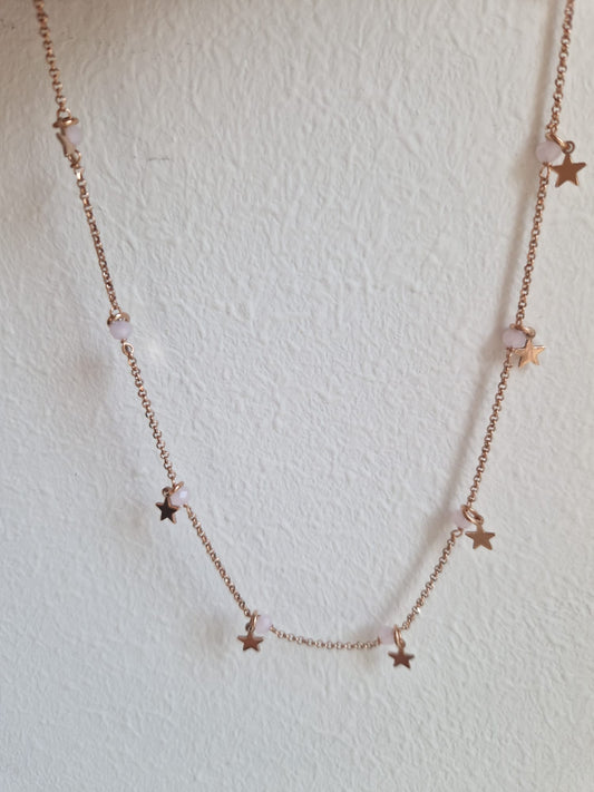 Una collana in oro rosa con piccole stelle e perle rosa.