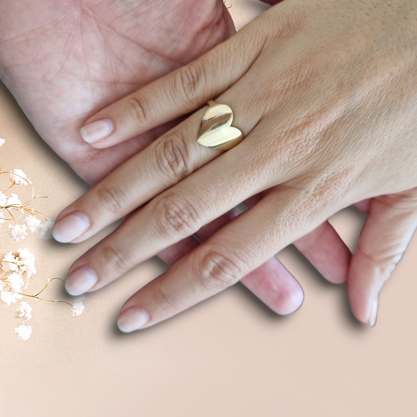 Anello a forma di cuore su una mano, con un'altra mano sotto.