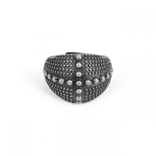 Anello scuro a fascia larga, con una texture a piccole sfere e un motivo a croce di sfere più grandi.