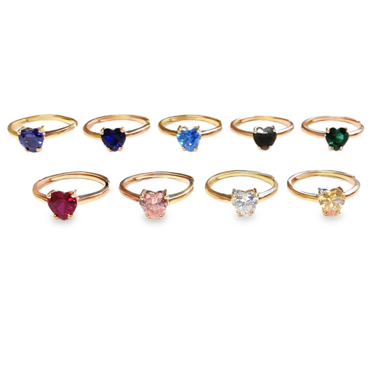 Anelli in oro con pietre a forma di cuore, in vari colori: blu scuro, azzurro, nero, verde, rosso, rosa, bianco e giallo.