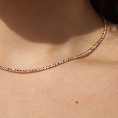 Collana tennis in oro e diamanti indossata da una donna.