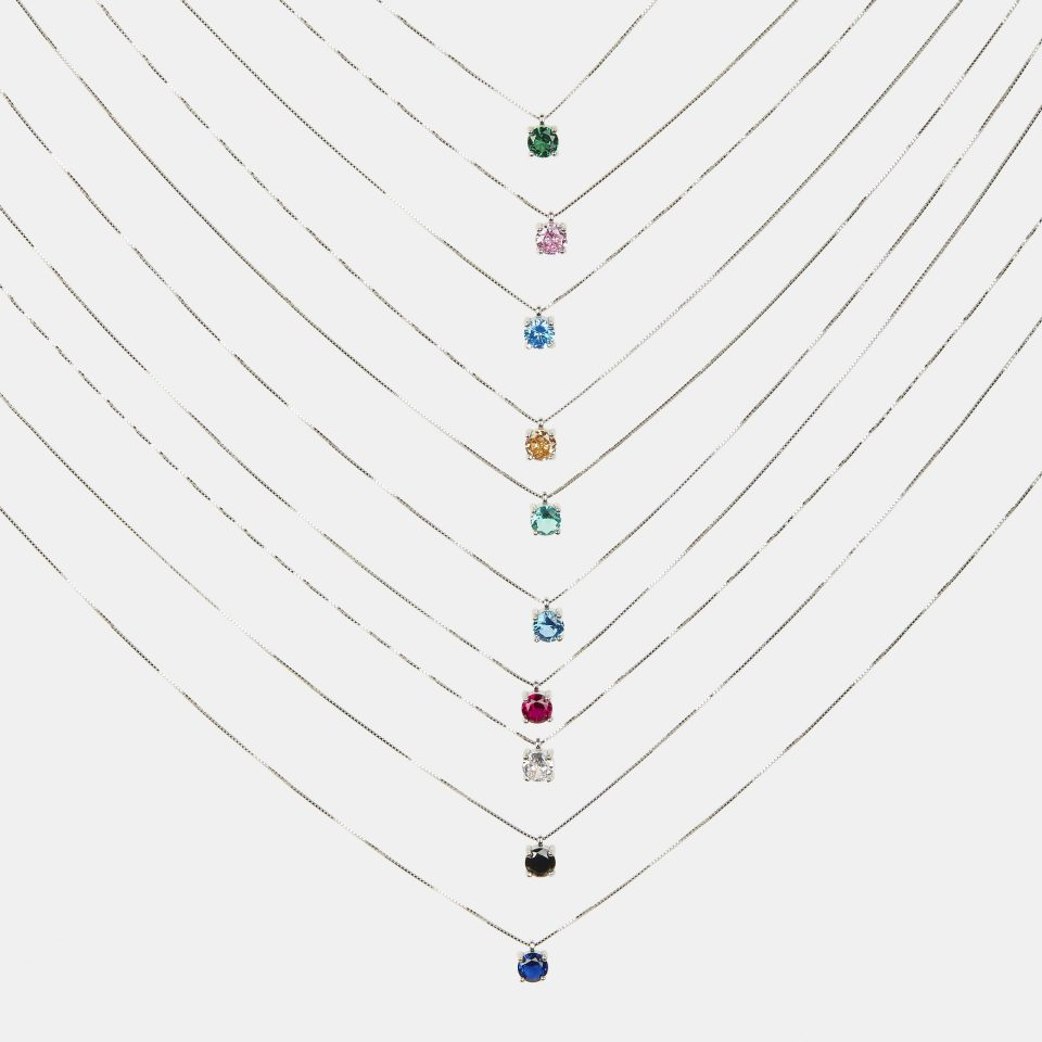 Dieci collane d'argento con pendenti a punto luce di diversi colori, tra cui verde, rosa, blu, giallo e nero.