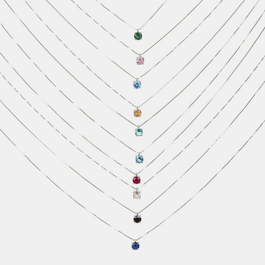 Dieci collane d'argento con pendenti a punto luce di diversi colori, tra cui verde, rosa, blu, giallo e nero.