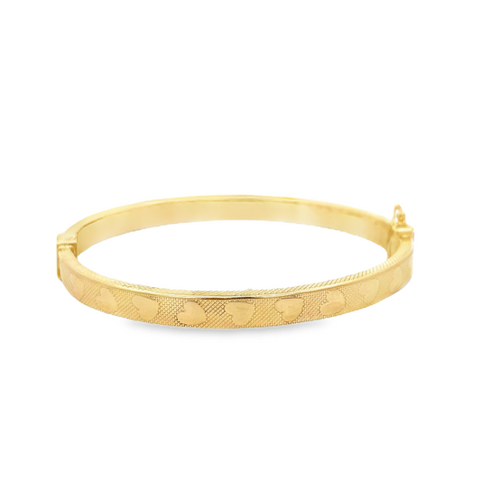 Bracciale rigido in oro giallo con decoro a cuori e texture a rombi, chiusura con gancio laterale.