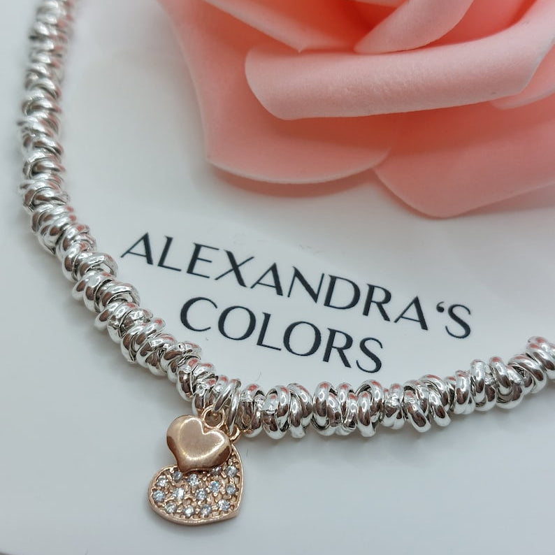 Braccialetto d'argento con un ciondolo a cuore in oro rosa, metà lucido e metà tempestato di brillanti.