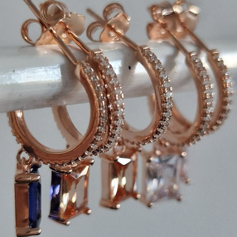 Orecchini a cerchio in oro rosa con zirconi e pendenti colorati.