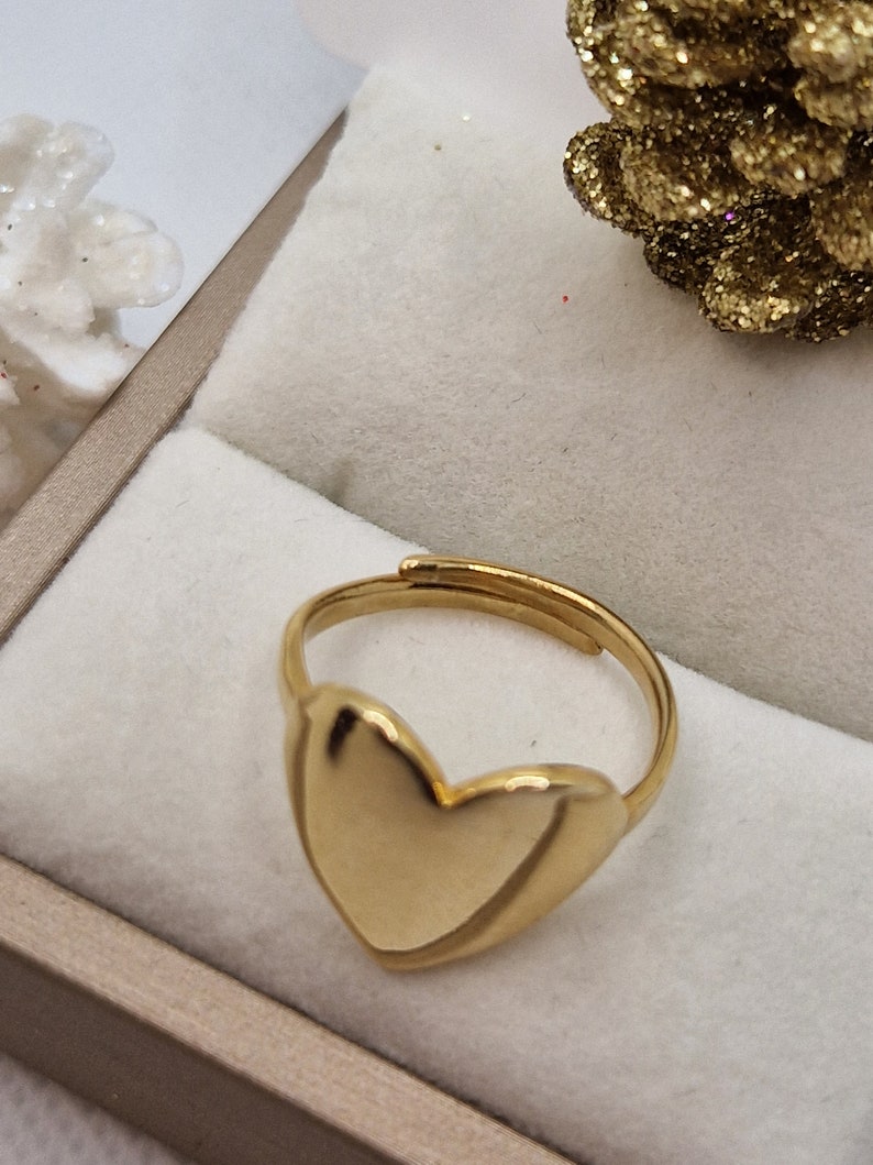 Anello dorato regolabile con cuore a sigillo in un cofanetto.