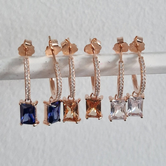 Orecchini a cerchio pendenti con zirconi in tre varianti di colore: blu, ambra e bianco.