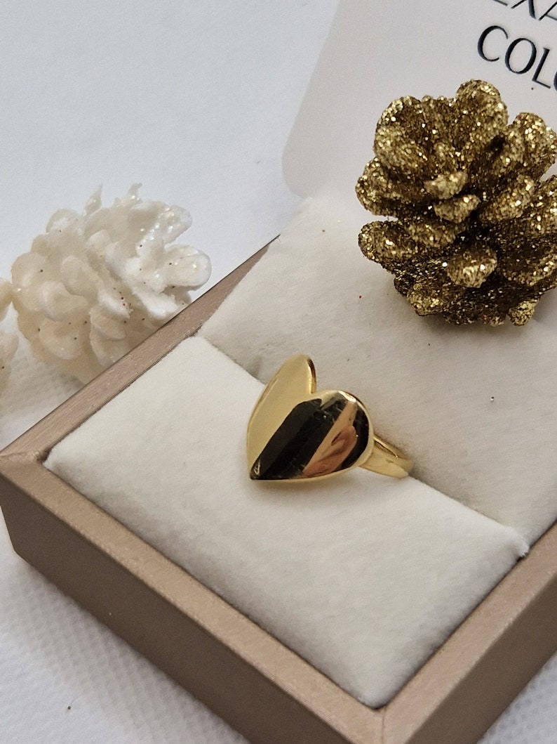 Anello dorato a forma di cuore in una scatola.