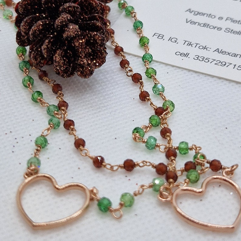 Collana artigianale con due fili di perle verdi e marroni, due ciondoli a cuore e decorazioni a forma di pigne glitterate.