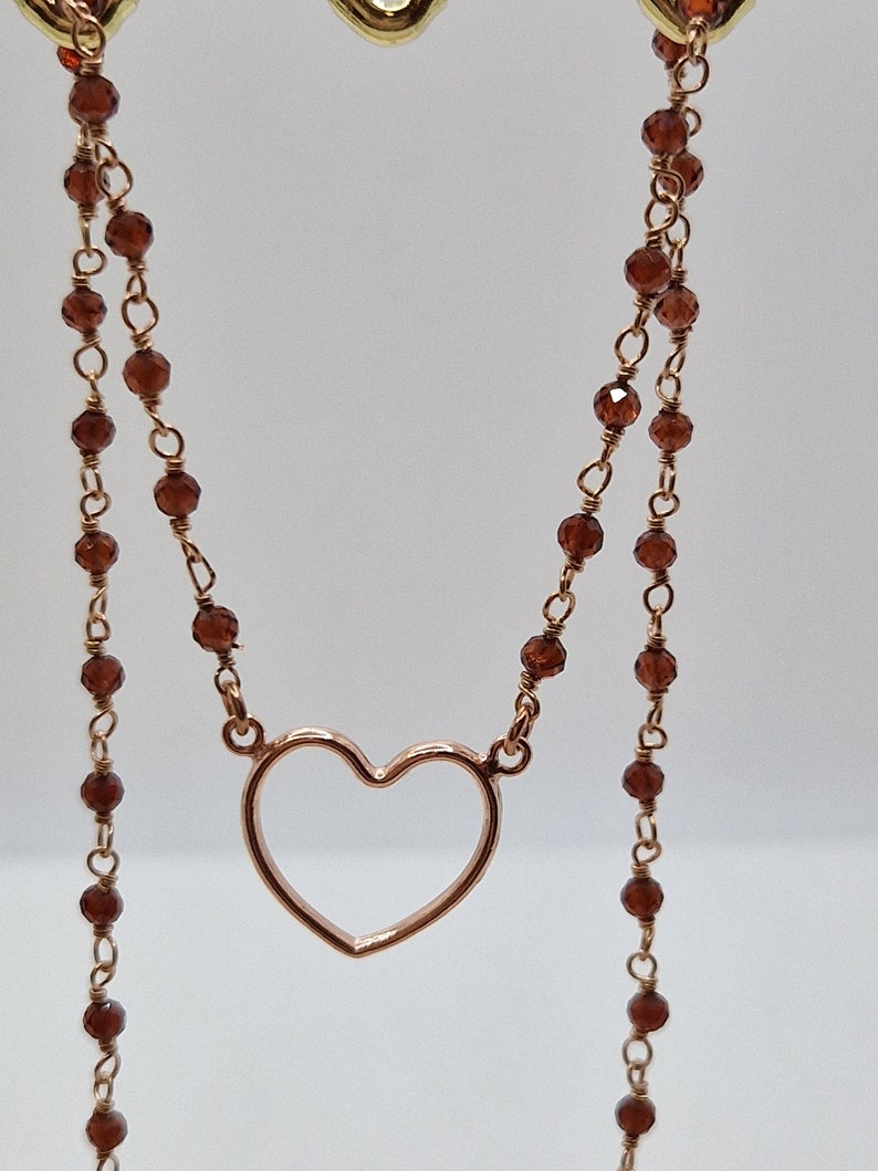 Collana a doppio filo in oro rosa con perline di granato e un ciondolo a forma di cuore.