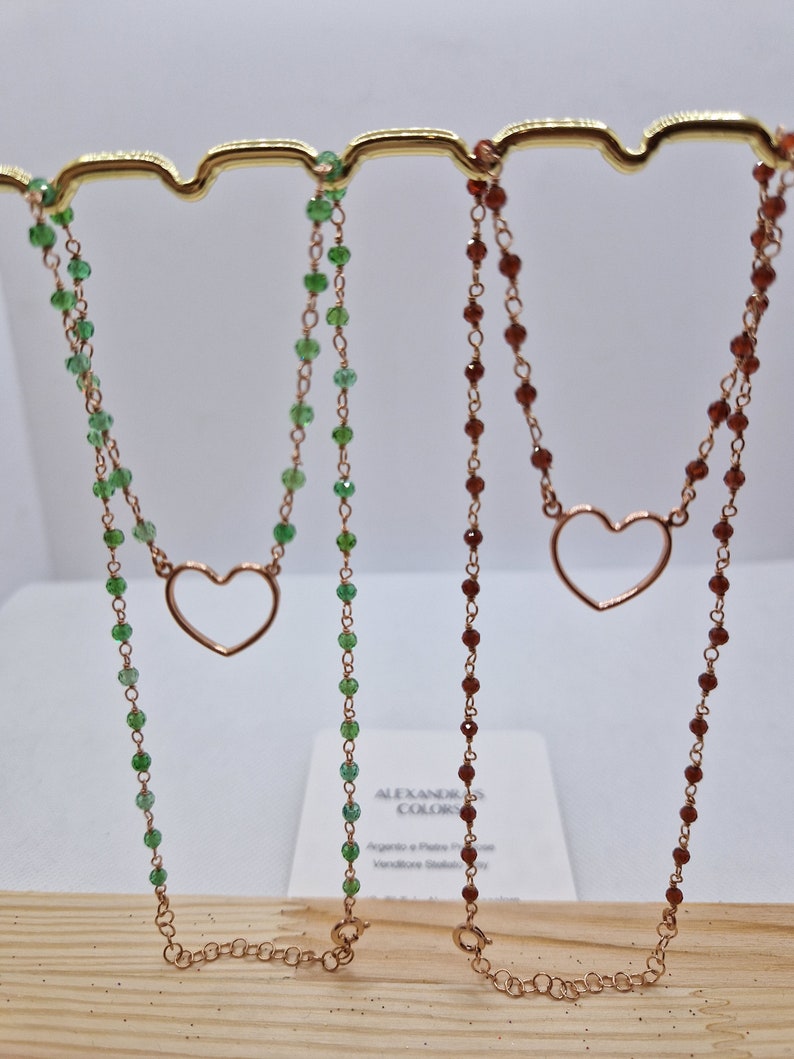Collane in argento placcato oro rosa con cuori aperti e perline verdi e marroni.