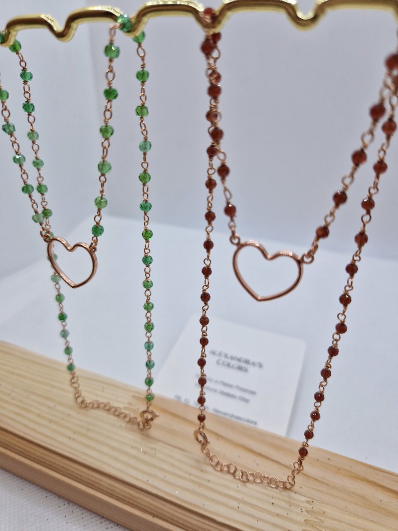 Due collane con ciondolo a cuore in rame, una con perle verdi e una con perle marroni.