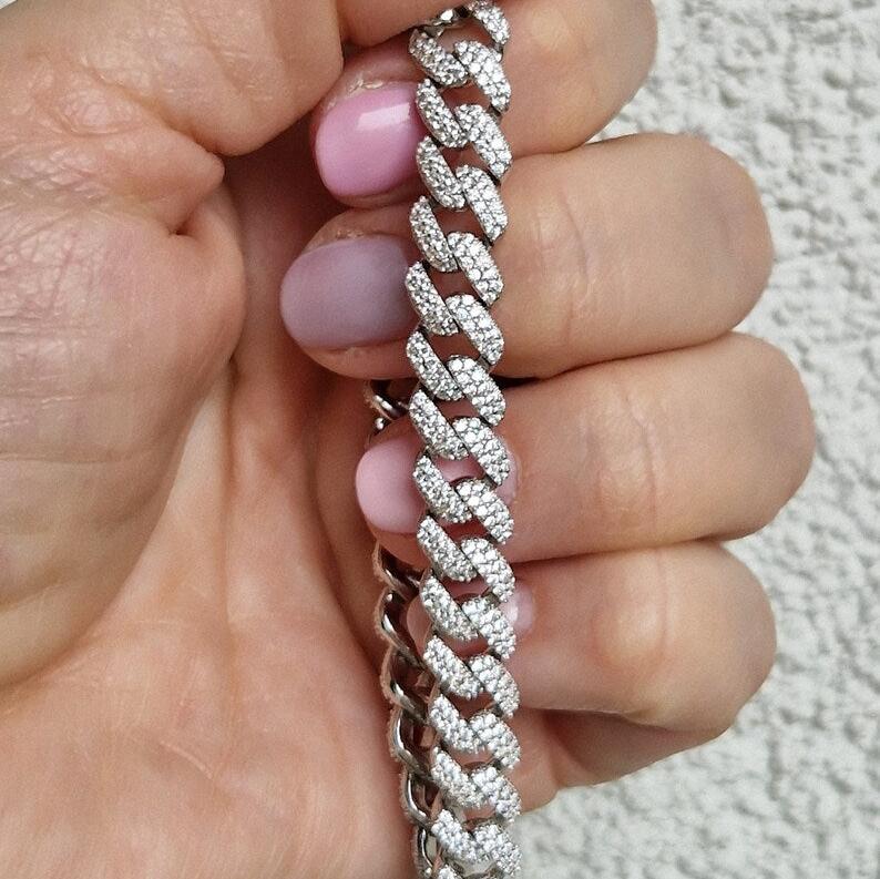 Braccialetto a catena d'argento con pavé di diamanti tenuto in mano.