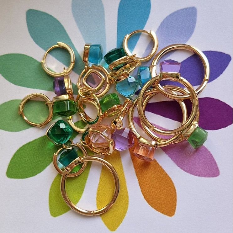 Piccolo assortimento di orecchini a cerchio dorati e charms di pietre colorate.