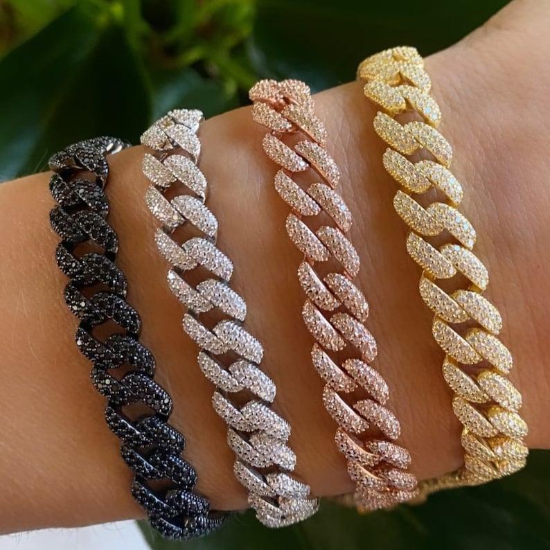 Quattro bracciali a catena cubana con strass in nero, argento, oro rosa e oro giallo.
