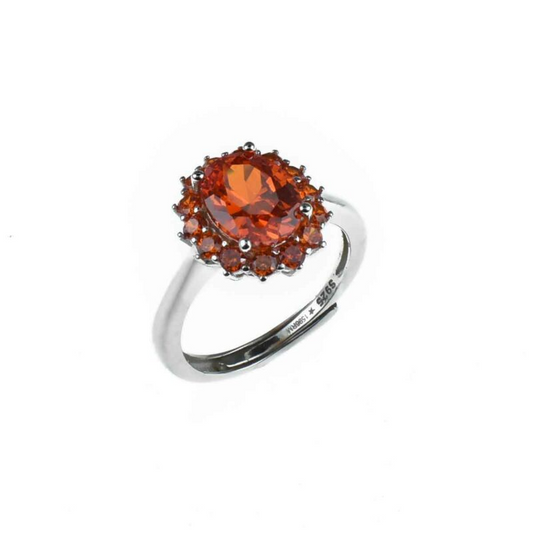 Anello in argento con una grande pietra centrale ovale color arancione circondata da gemme più piccole dello stesso colore.
