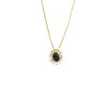 Collana in oro con ciondolo ovale blu scuro circondato da perle bianche.